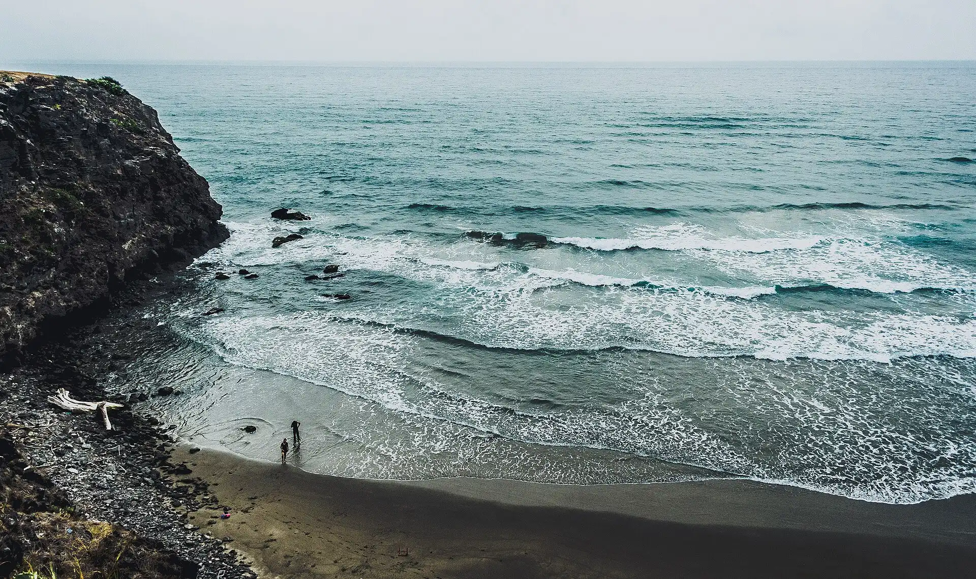 A dark-sand cove and rocky headland on the Pacific coast of Mexico.