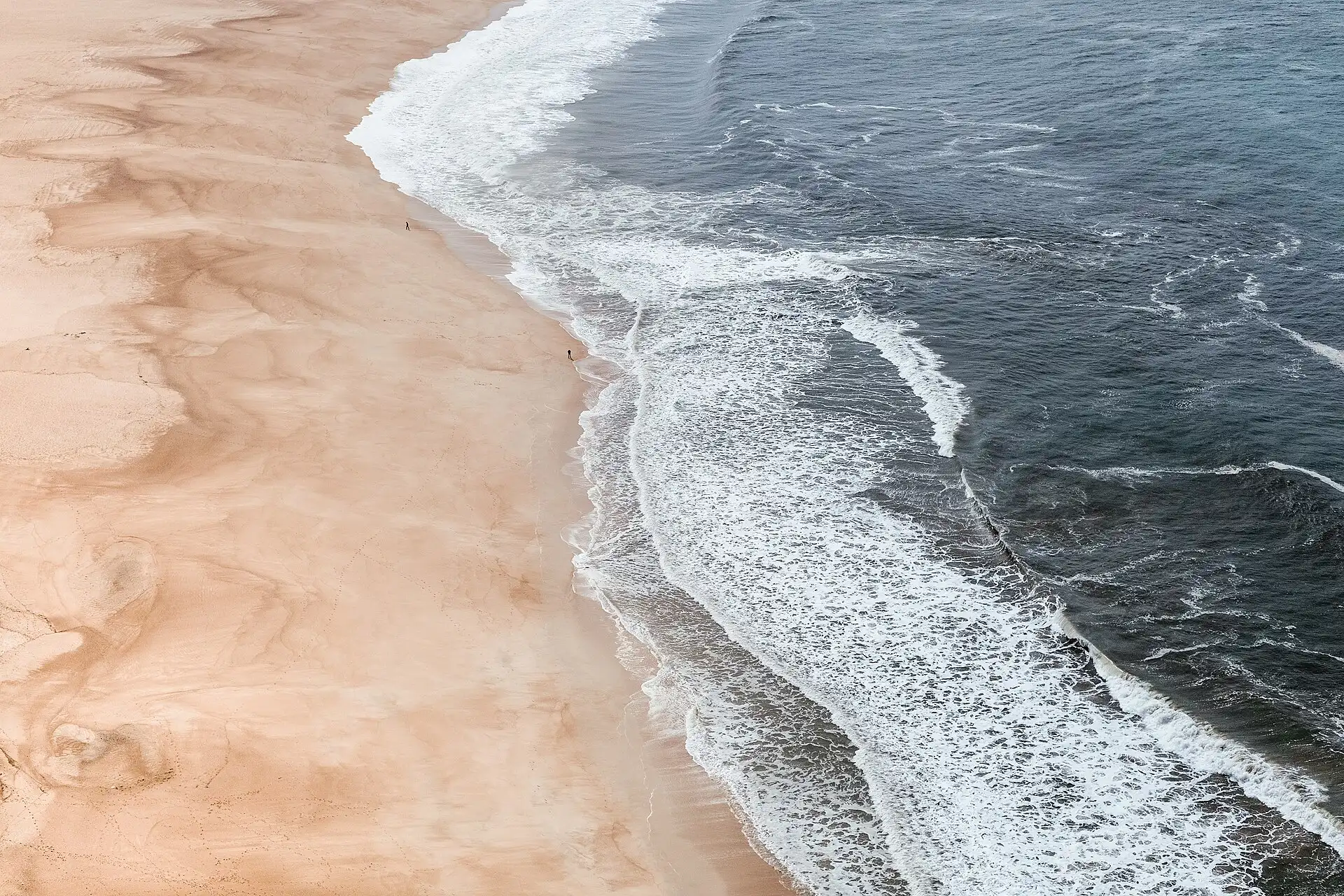 The beach at Nazaré, Portugal, from above, where the sand meets the surf.