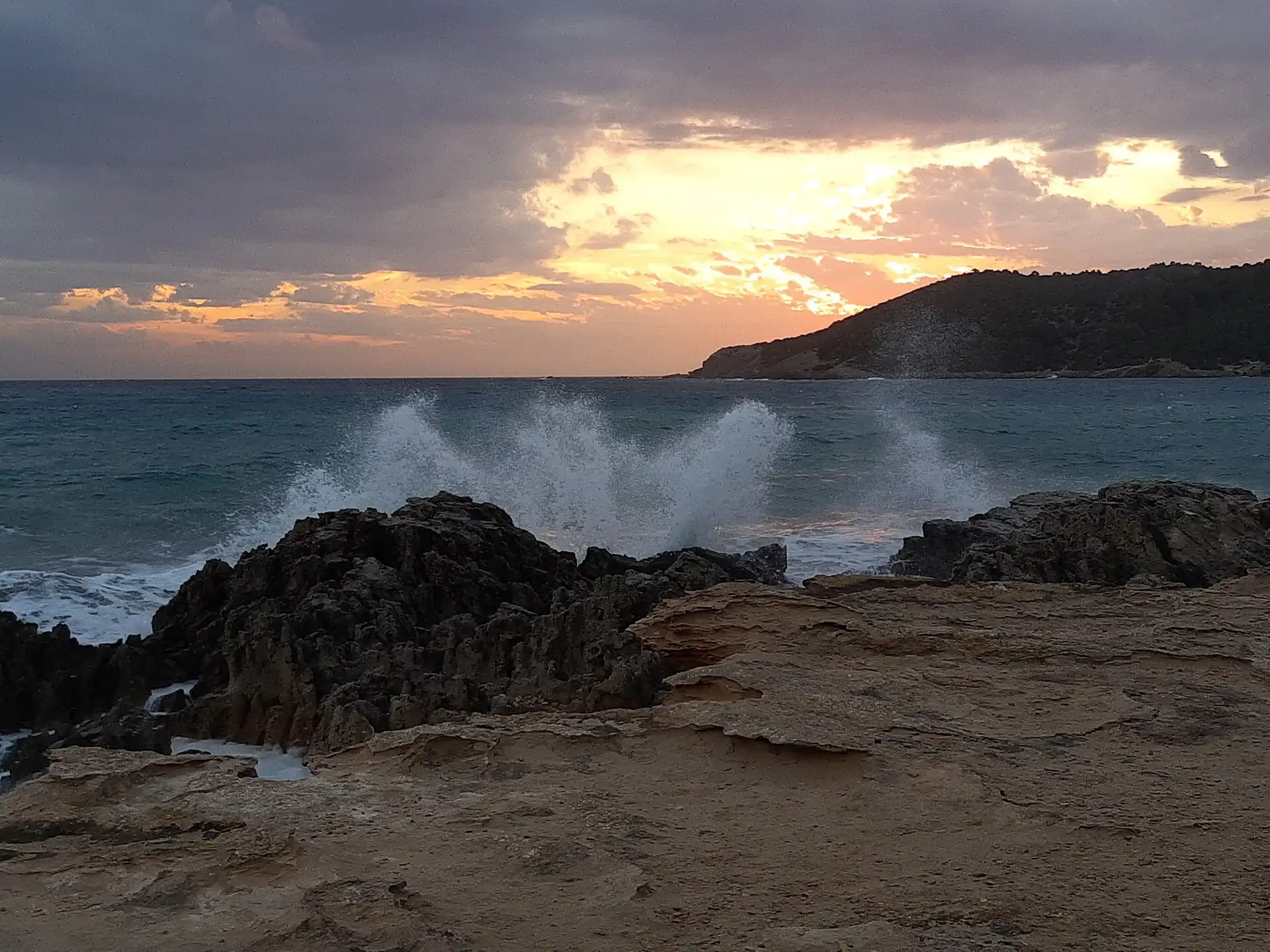 Waves breaking on the rocks at Platja de ses Salines, Ibiza, at sunset.