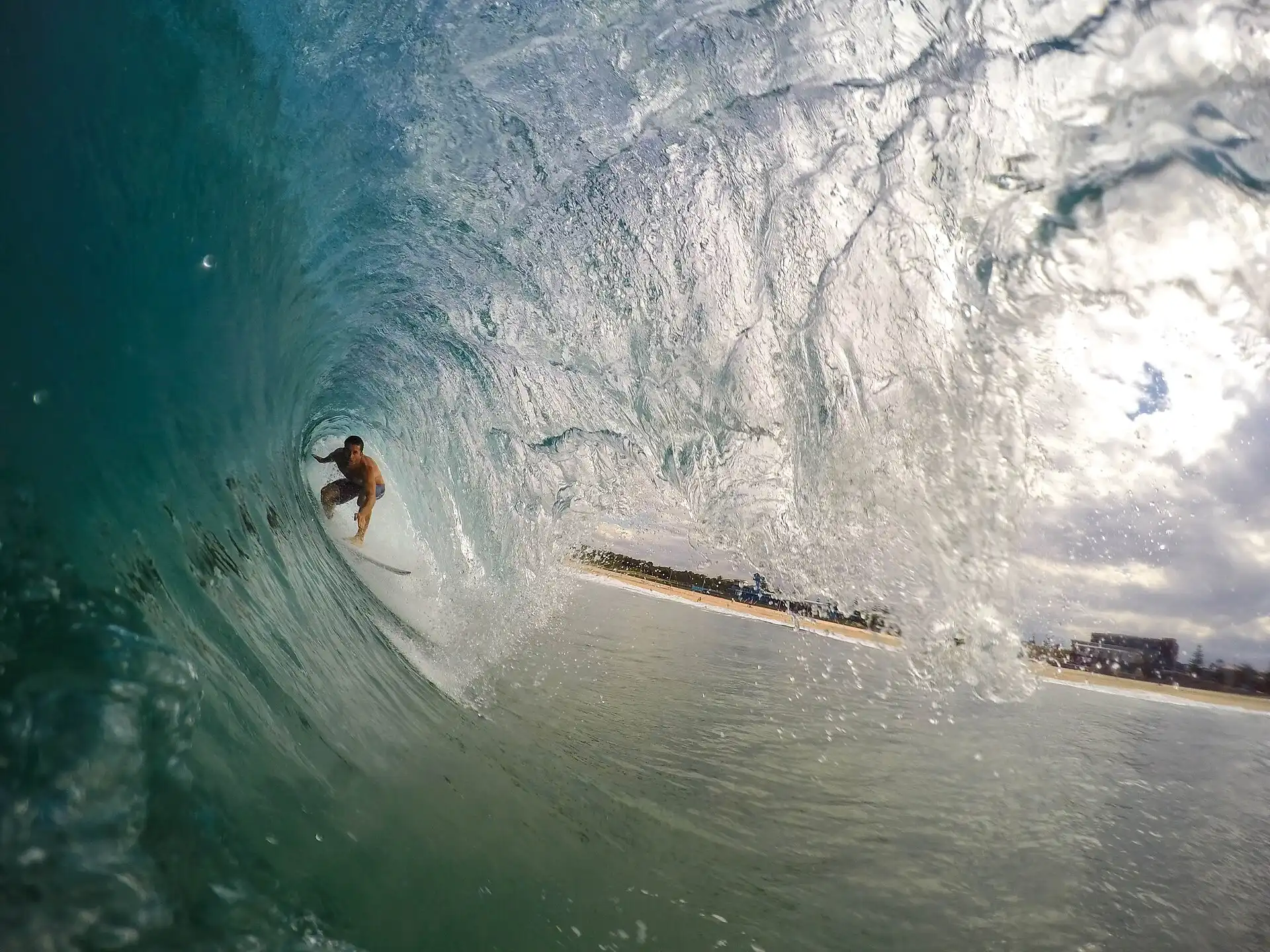 A surfer crouched inside the barrel of a breaking wave.